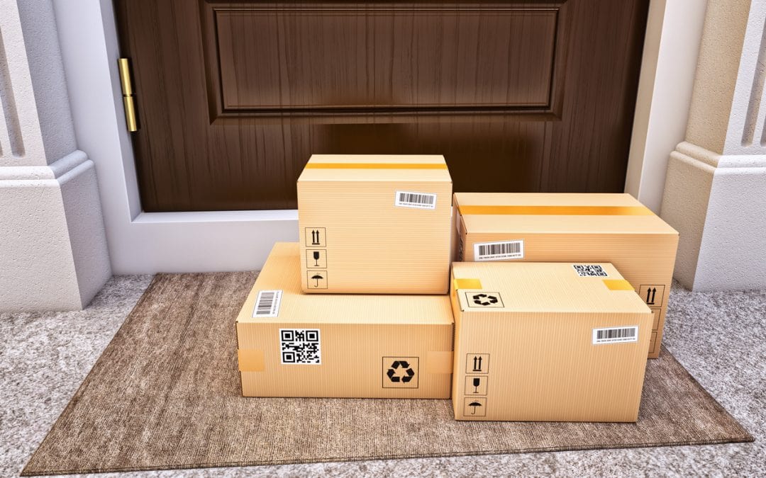 A stack of delivered packages sitting on a porch.