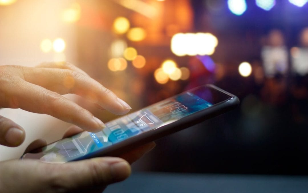 A picture of a smartphone being held and used for ecommerce purchasing
