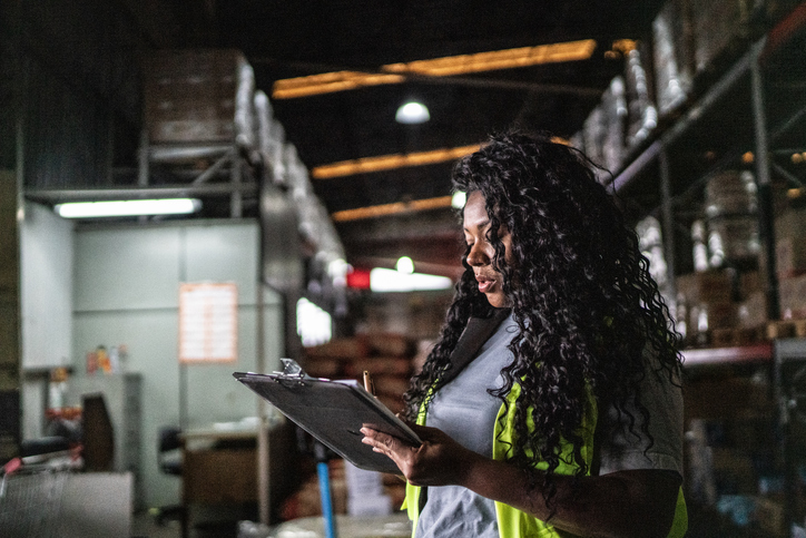 Warehouse worker writing in a clipboard
